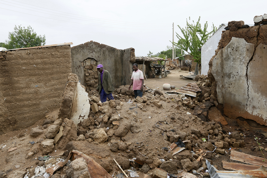 People walk pass the rubble of houses destroyed by Boko Haram militants in Garaha, Adamawa state, Nigeria.  UNHCR / George Osodi