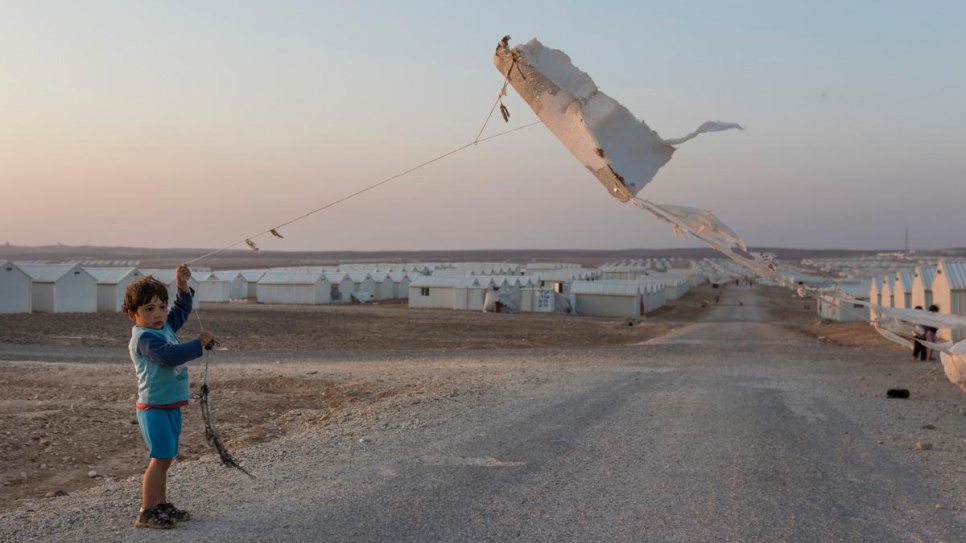 A young Syrian refugee boy flies a homemade kite made from a piece of insulation at Azraq camp in Jordan.