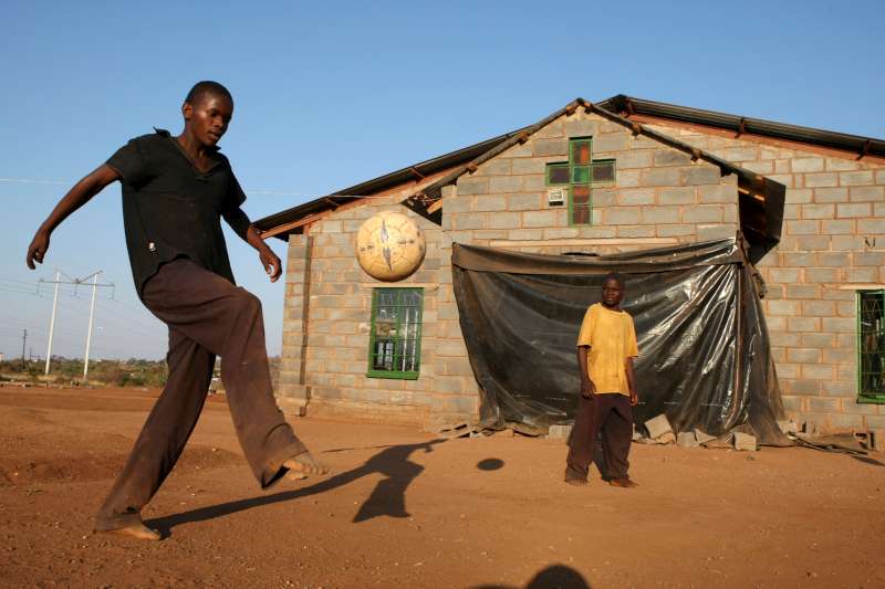 Teenager Conwell plays football at the Boy's Shelter in Nancefield, Musina, South Africa. The shelter houses more than 200 boys aged up to 16. Most of the boys crossed the border unaccompanied. They are given food, shelter and lessons. 