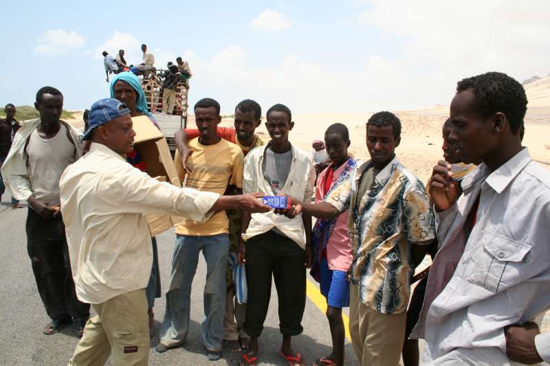 Des employés d'une organisation non gouvernementale yéménite distribuent de la nourriture aux nouveaux arrivants somaliens et éthiopiens, avant de les emmener au centre d'accueil de Mayfa'a.