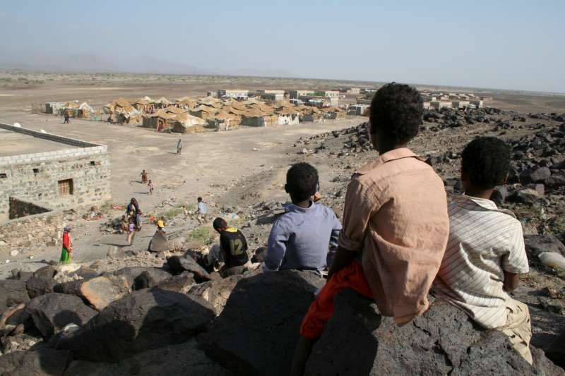 De jeunes Somaliens et Éthiopiens juchés sur une colline, d'où l'on aperçoit la section des nouveaux arrivants du camp de réfugiés de Kharaz.