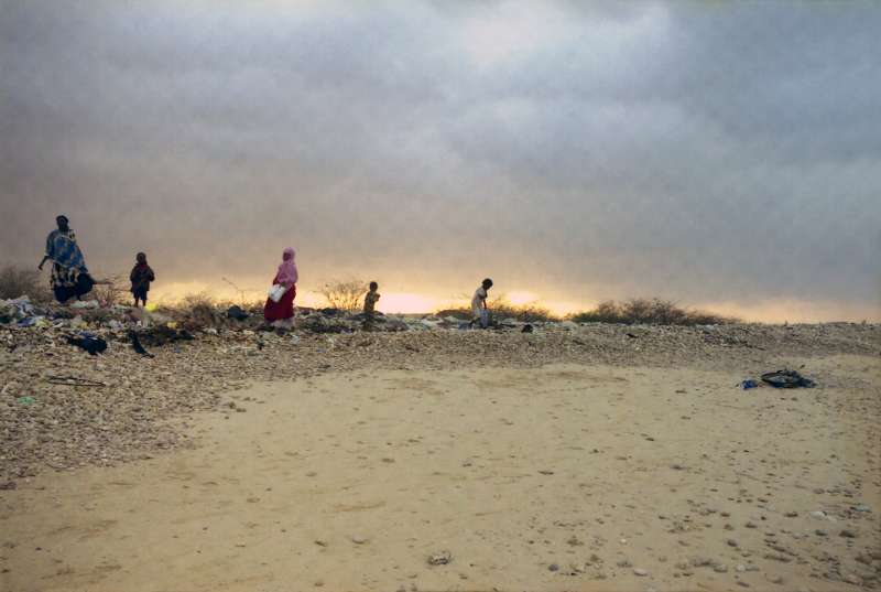 Sur une plage balayée par le vent près de Bossasso, des femmes et des enfants, hébergés aux alentours dans un camp accueillant des déplacés, cherchent des restes de charbon de bois et du bois rejeté par la mer pour cuire un repas.
