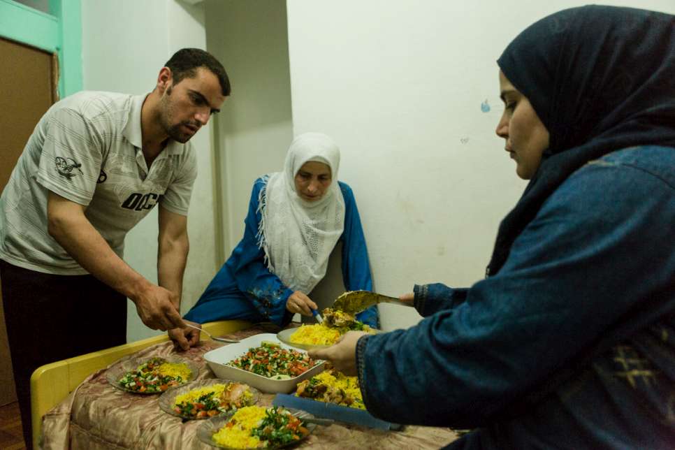 Yusra, 35, helps her sister-in-law serve dinner along with brother Zaher at the apartment they share with their families.