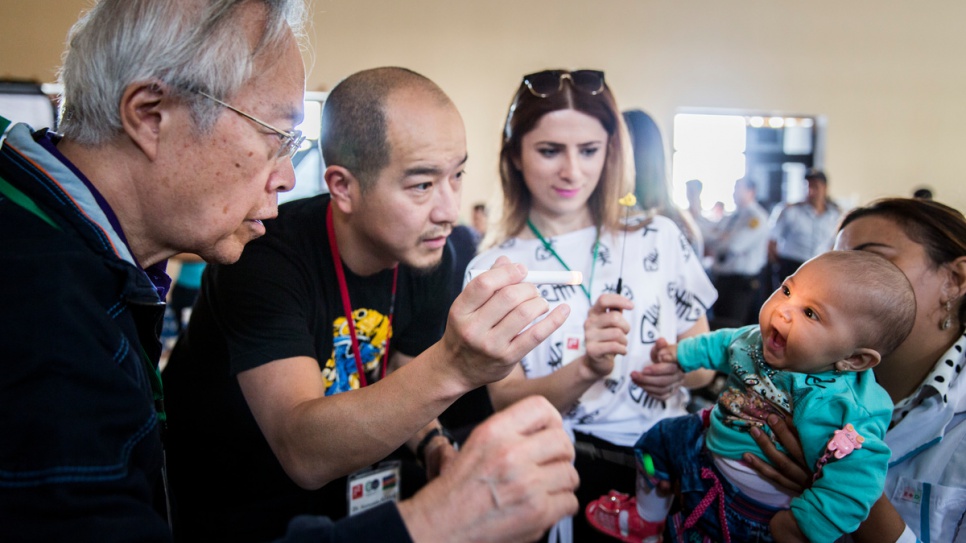 A baby has her eyes tested by Akio Kanai and his son. In May 2016, during six days of eye testing, Kanai's team screened 2,882 people and dispensed 2,433 eyeglasses.