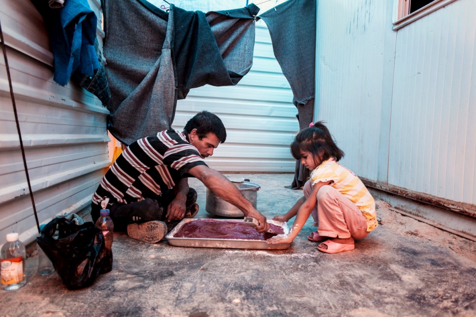 Abu Rabee' pours "raha" mixture into a tray with the help of his daughter Rawaa, at his caravan at Za'atari refugee camp in Jordan.