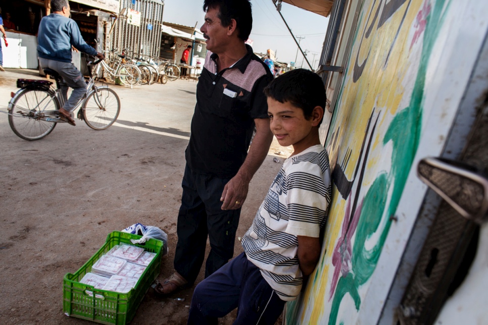 Faris and his father, Abu Rabee', wait for customers to buy their handmade "raha" in the main shopping street at Za'atari refugee camp in Jordan.