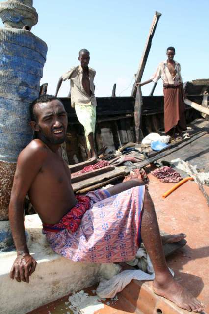 Newly arrived Somalis and Ethiopians rest on their smuggler's boat, which was forced ashore by the Yemeni armed forces. The smugglers escaped in a dinghy.