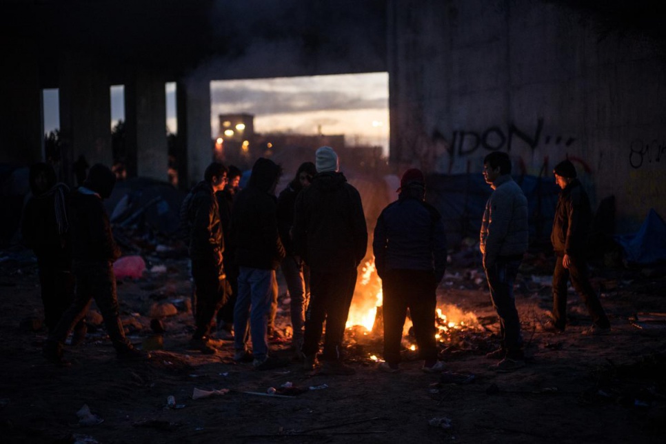 Young asylum-seekers burn rubbish and discarded tents to warm themselves at the camp in Calais, a temporary home for approximately 4,500 refugees and migrants.