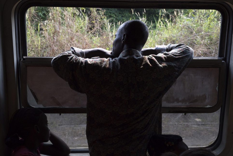 A former refugee looks out the window of a train as it travels from Kinshasa, DRC, towards his home of Angola. Nearly 500 others are travelling with him.