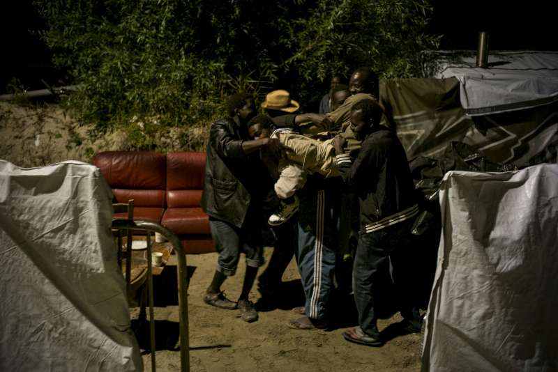 Asylum-seekers from Sudan celebrate in the so-called jungle in Calais. One of their friends is leaving for an accommodation centre for asylum seekers in the morning.