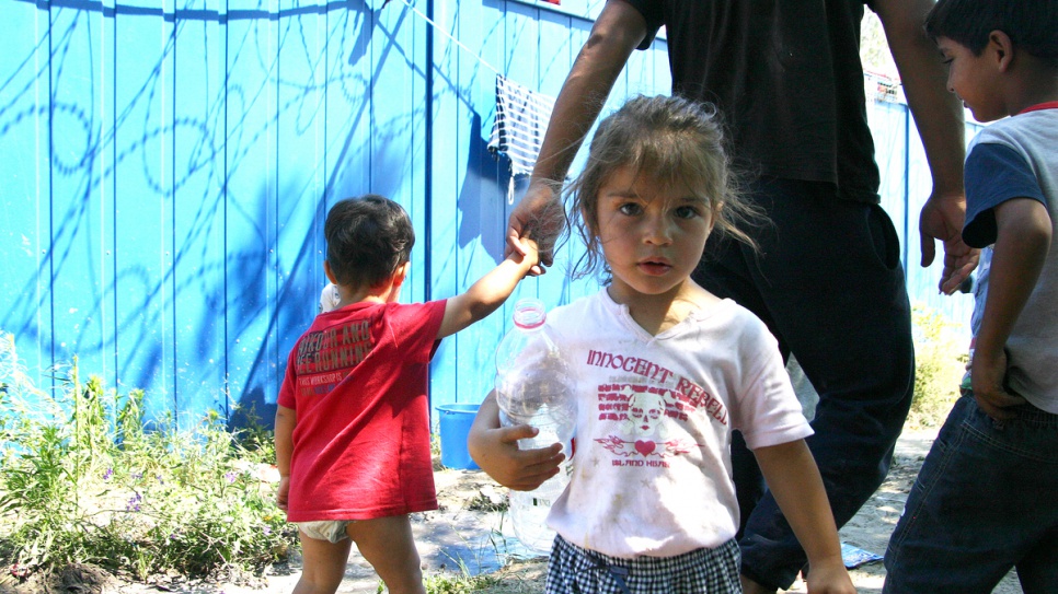 A young girl turns to the camera on her way to collect water at Röszke makeshift refugee camp.