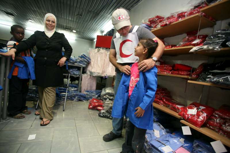 Syria / Iraqi refugees / A Red Crescent volunteer helps a young Iraqi find a school uniform in the correct size. To encourage poor Iraqi families to register their children in school, UNHCR plans to provide financial assiance, uniforms, books and school supplies to Iraqi refugees registered with UNHCR. /2007