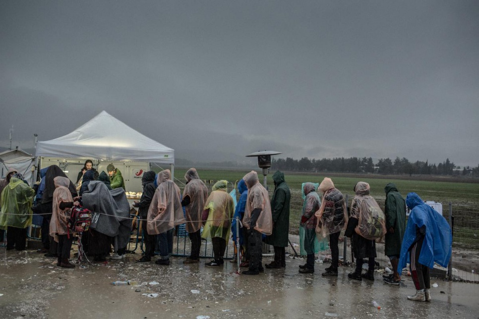 Refugees and migrants queue for food during heavy rain in Idomeni, Greece.