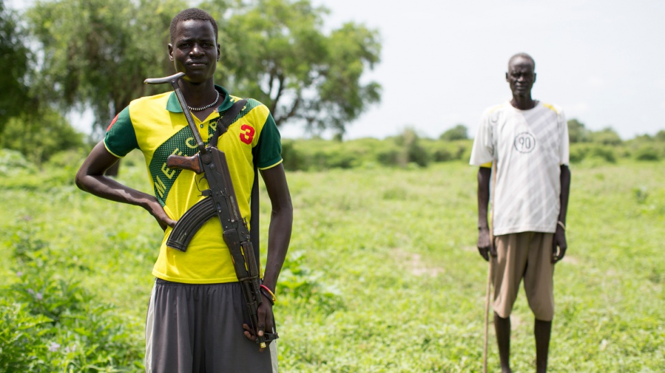 Chuol Galuak, 24, stands in front of his father Gatluak Ruei Kon in Old Akobo. "When the war broke out, I lost contact with my father," he says. "Being the oldest son, I was forced to take charge of my family. I was forced to drop out of school and get a gun. I am so happy that my father is back home."