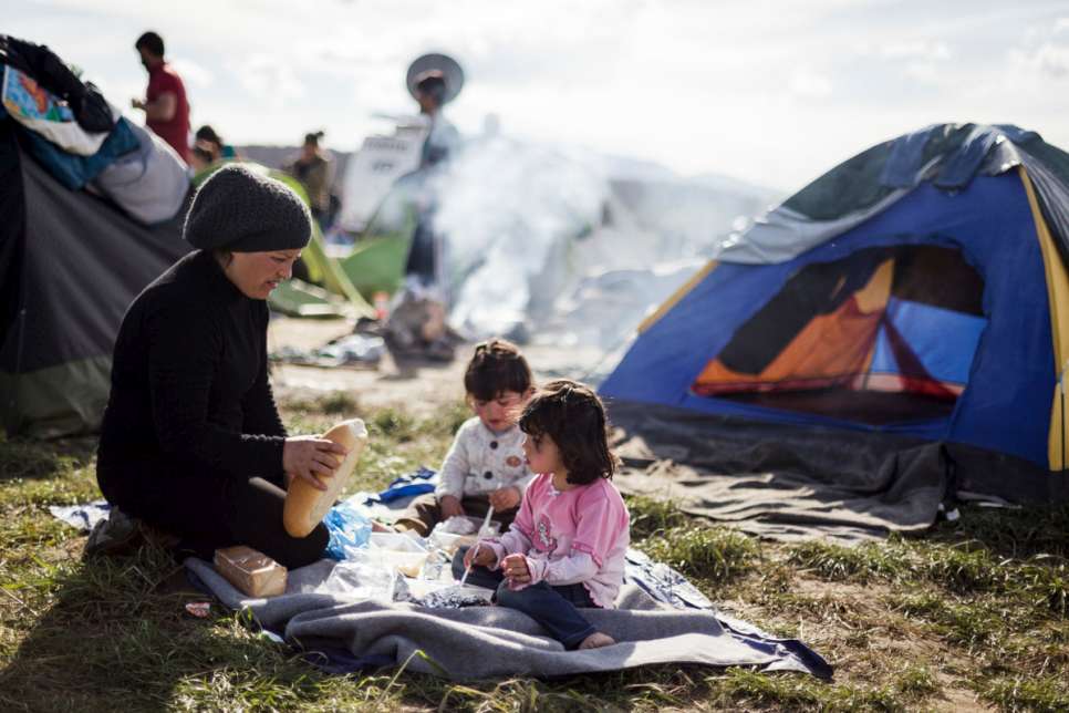 Nisrine feeds her two youngest children, Adib, 3, and Sedra, 4, outside the small tents the family sleep near the Idomeni transit station.