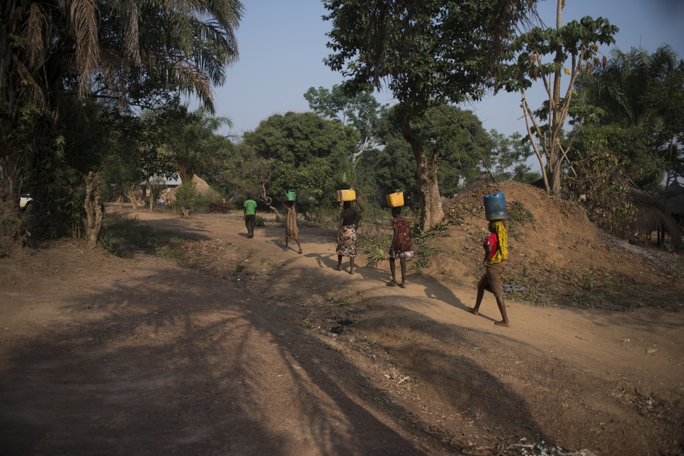 A family of refugees from South Sudan fetch water from the well near the home of the Congolese family that is providing them with shelter in Dungu.