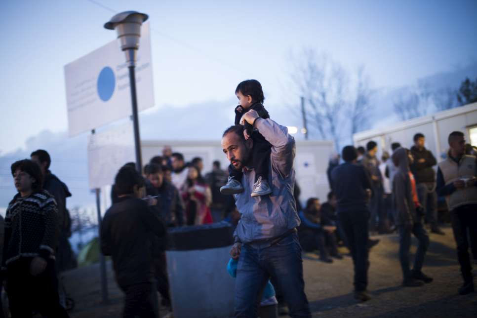 A man carries his young son on his shoulders at the Idomeni border station.
