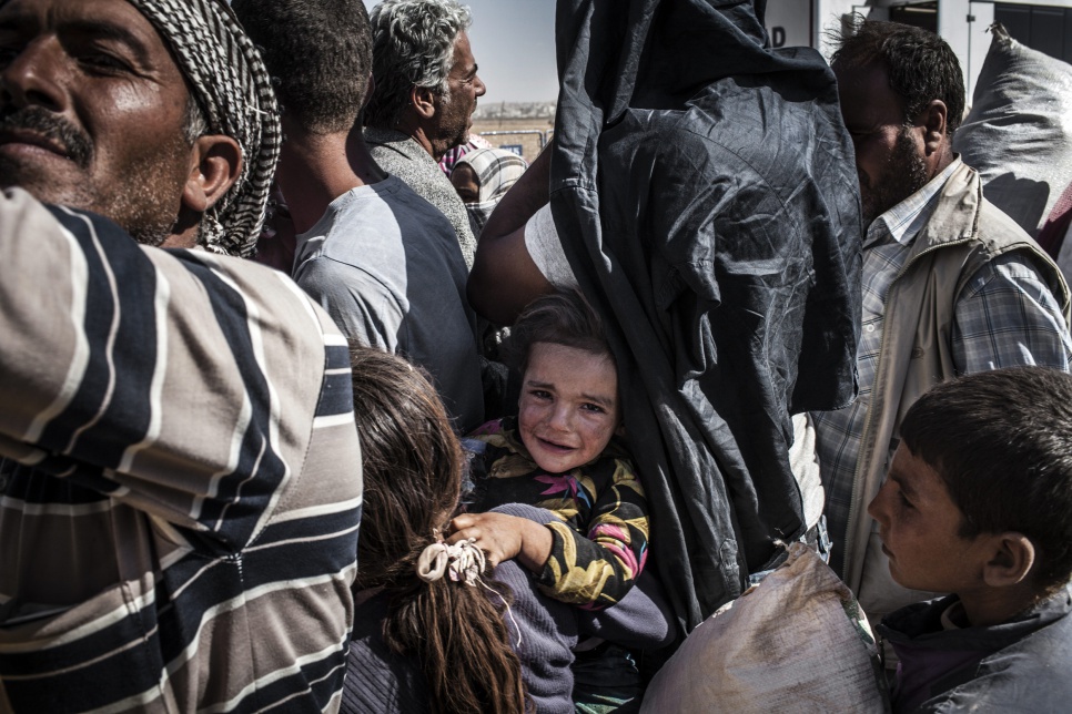 Syrian Kurdish refugees wait in a holding area after crossing the border from Syria into Turkey.