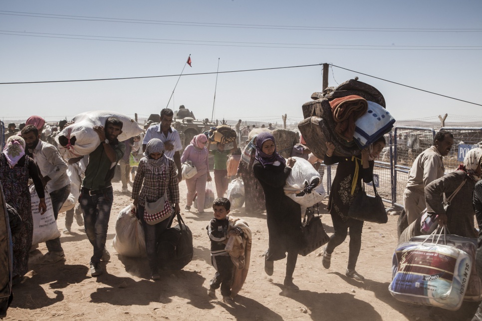 Syrian Kurdish refugees cross into Turkey from Syria near the town of Kobani.