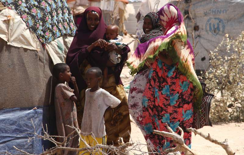 Mères déplacées internes et leurs enfants, au site d'Halabokhad, à Galkayo. On voit à l'arrière-plan leurs logements improvisés.