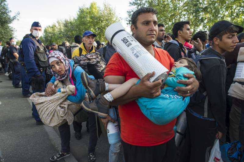 Hoping to continue walking on to Budapest, newly arrived refugees and migrants are stopped by police and eventually convinced to spend the night outside an overcrowded registration centre in Hungary. 