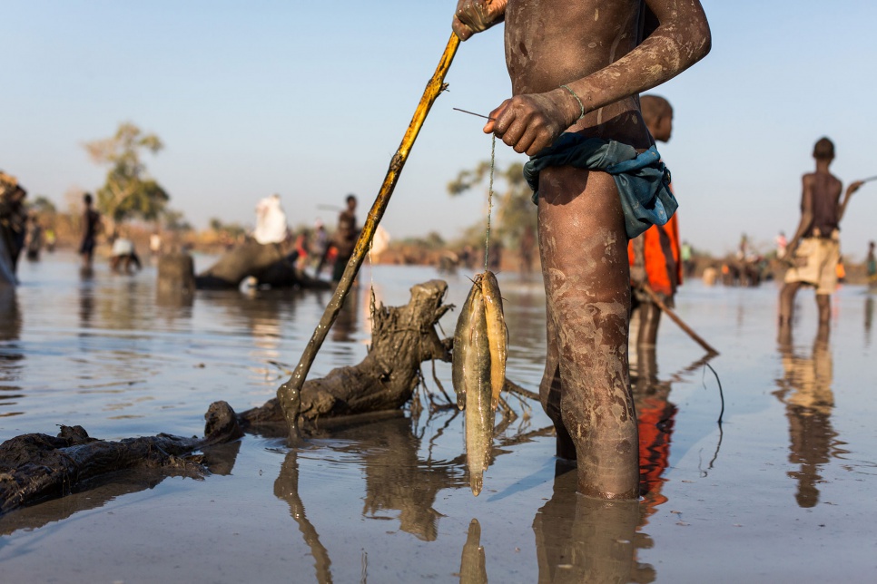 A young refugee from Sudan holds his catch of mudfish in a shallow lake formed by floodwater near the town of Yida, South Sudan.