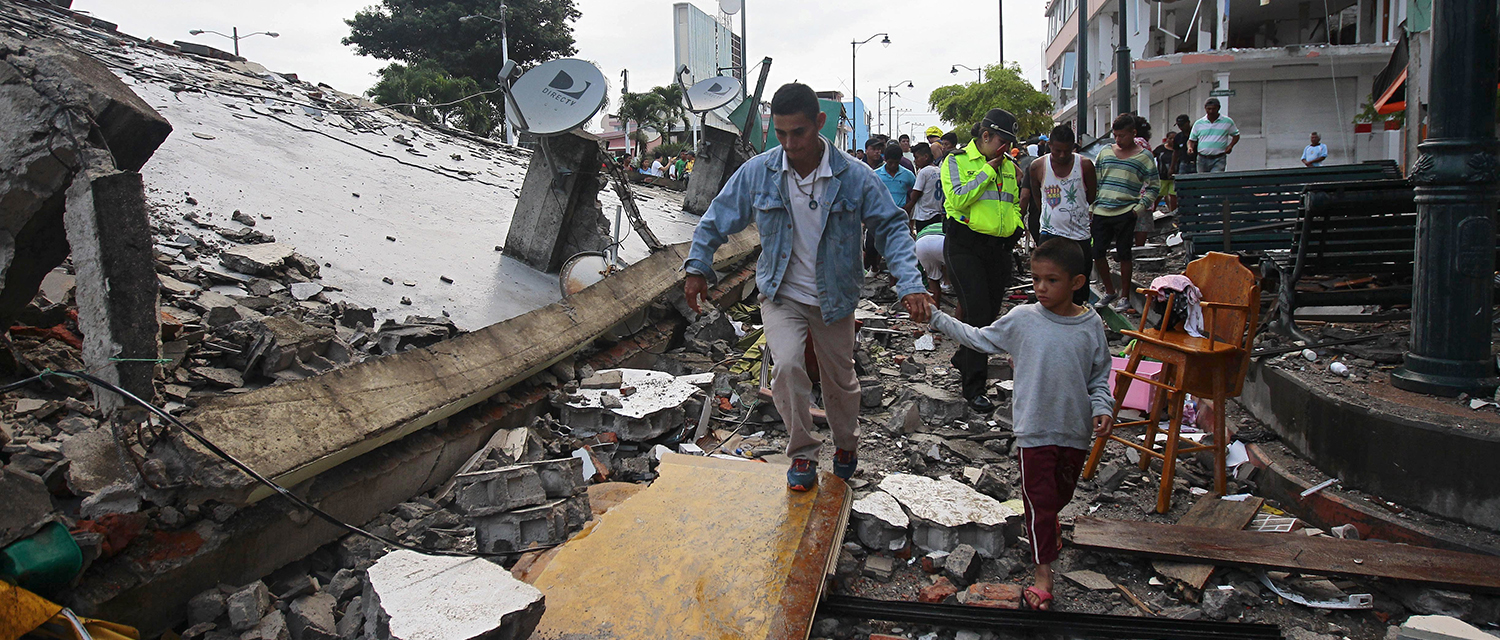 People walk among the debris of a collapsed building in the town of Pedernales, Ecuador, following a 7.8 magnitude earthquake.