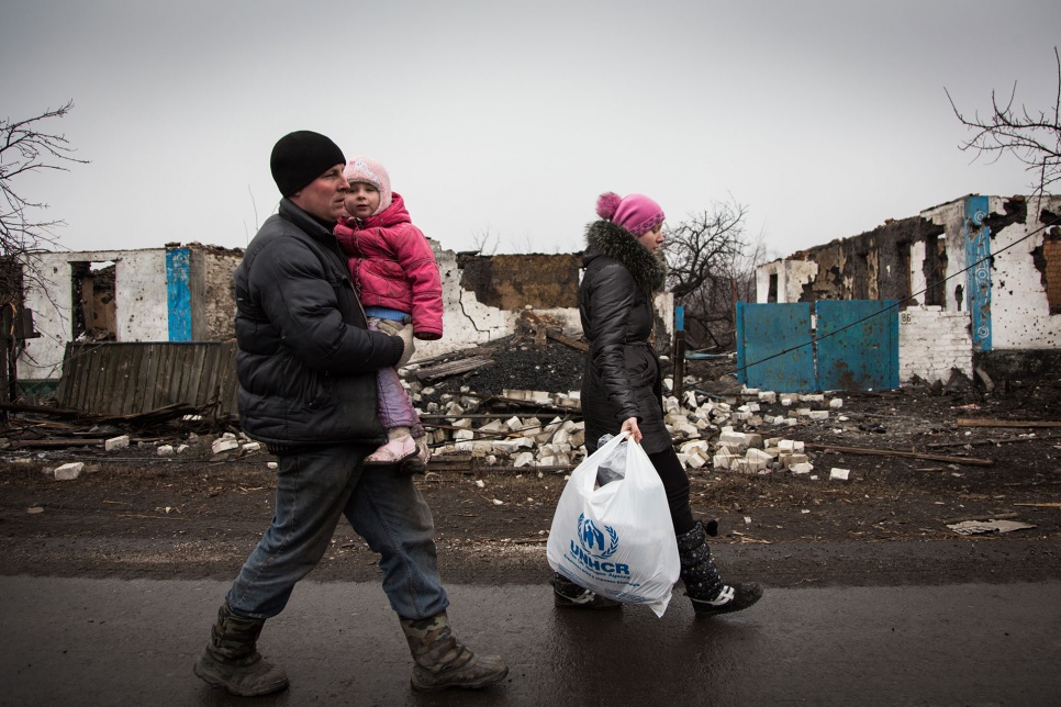 Sergei, Katia and daughter Sofia, 3, return home after receiving aid from UNHCR in Nikishino, eastern Ukraine. They are making repairs to their home in hopes of moving back in.