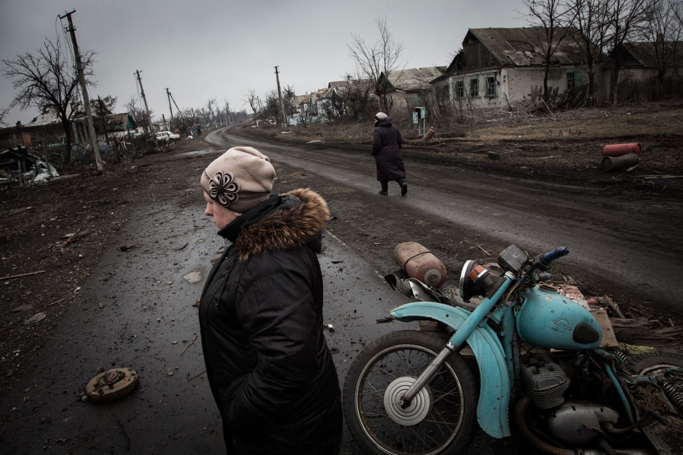 Residents walk along the main street of Nikishino village, in eastern Ukraine. The street is littered with unexploded mortars and mines.