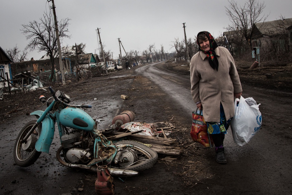 Galina walks along the main street in Nikishino village, in eastern Ukraine, after salvaging things from her ruined home. "I'm 65 and everything I have I'm holding."