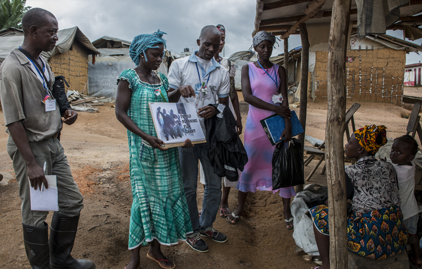 Jocelyn Konet (centre) and the community health team conduct a house-to-house visits at Little Wlebo camp, Liberia.  UNHCR / Diana Diaz