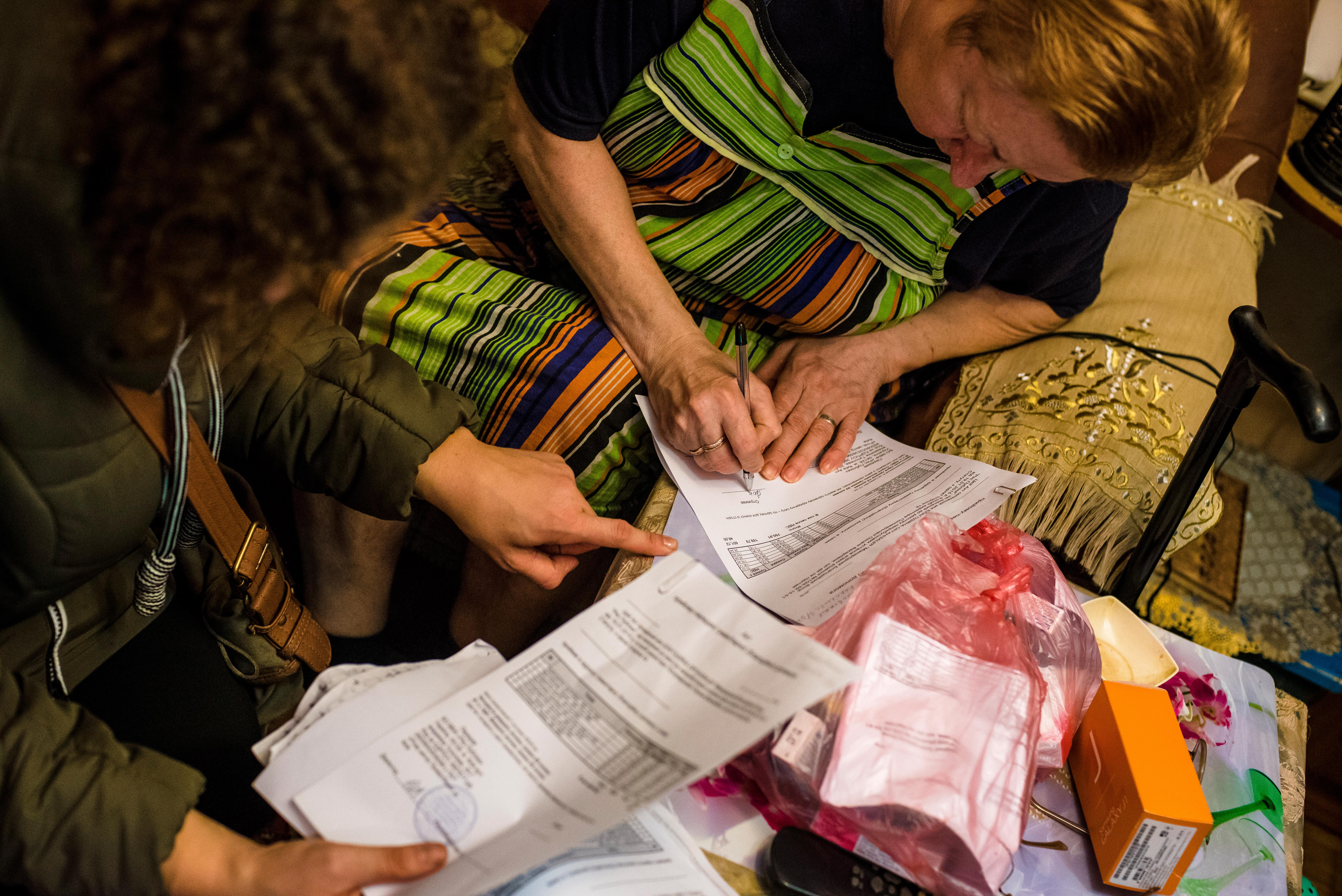 A woman in Avdiivka, Ukraine signs documents in order to receive much needed medicine provided by a Kyiv-based volunteer. 
© UNHCR/James Sprankle