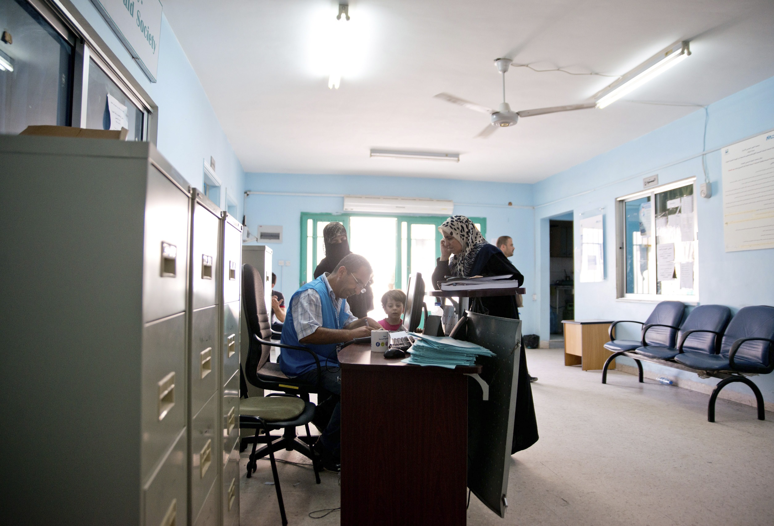 Jordan / Syrian refugees / UNHCR staff answer questions for refugees at a help desk in the city of Zarqa.  With approximately 75% of Jordan's refugee population living in urban settings, help desks like this one provide critical information and services to refugees in areas of protection, health, and registration. 15 August, 2013 / UNHCR / Jared J. Kohler / August 2013