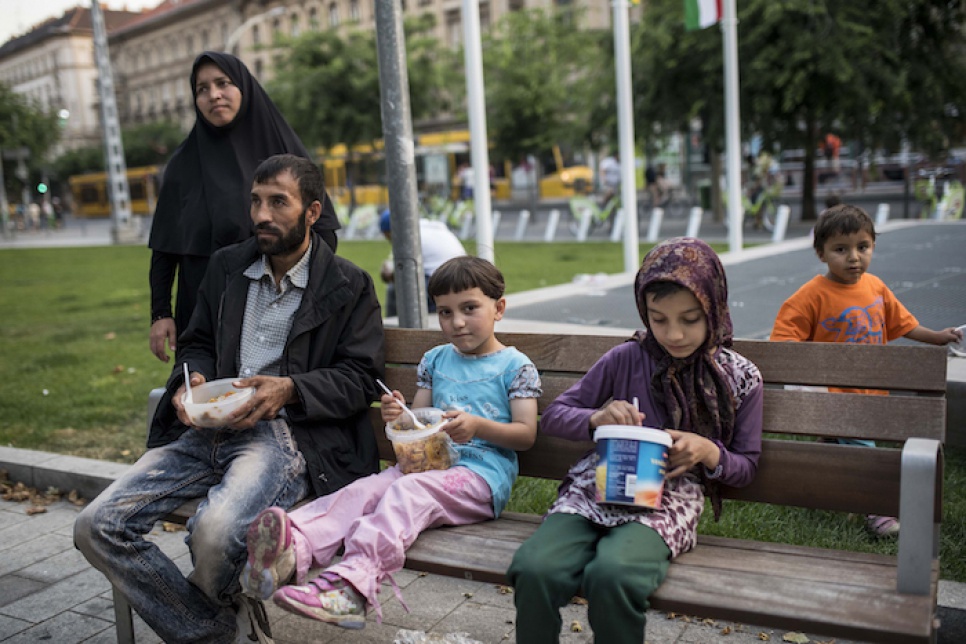 Asfar, his wife and their four daughters eat food cooked by volunteers. They fled Afghanistan and endured a perilous three-month journey to Europe.