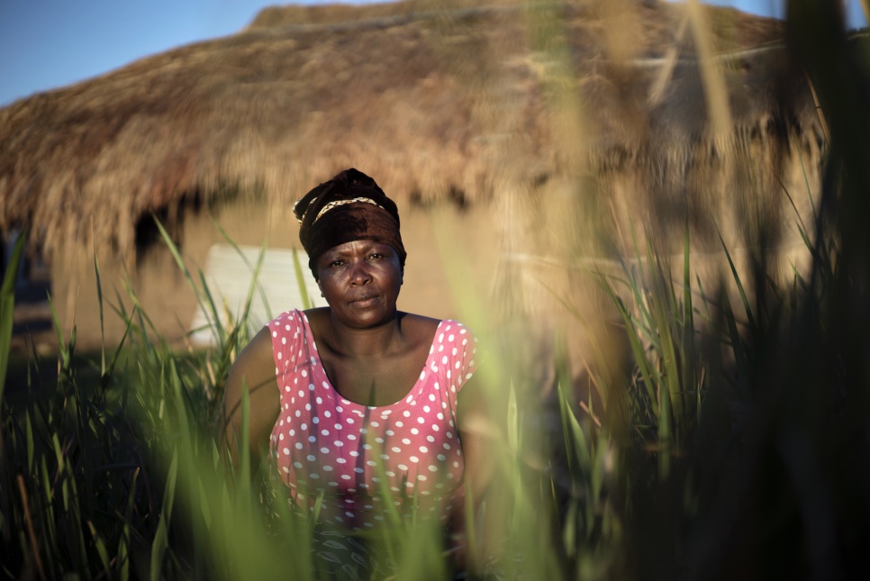 Okenge Sakina, 50, sits in front her new home in Lukwangulo. The walls are made of mud bricks and the thatched roof from grass.