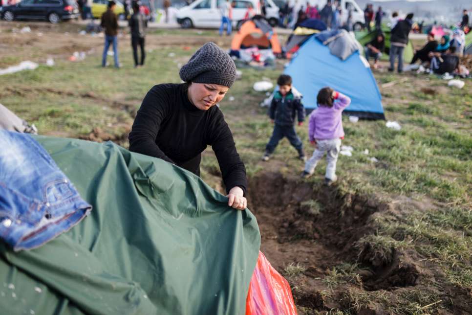 Nisrine spreads a raincoat over the tent to act as insulation against the rain and cold.