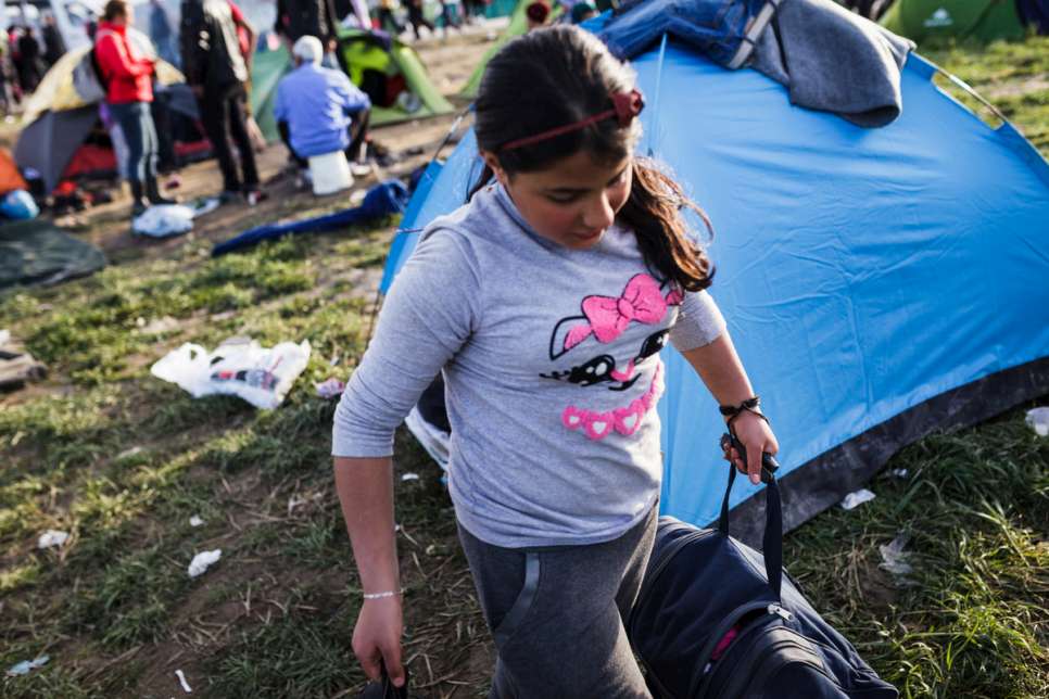 Medya, 13, carries a bag with clothes to the small camping tent she shares with her mother and four siblings.