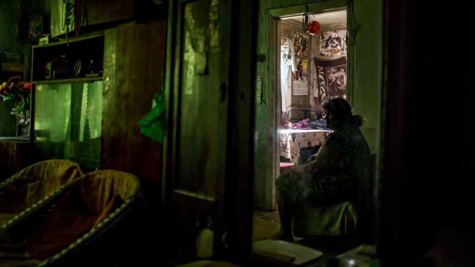 Anzhela's mother watches television in their house that was severely damaged in the 2014 hostilities in the eastern Ukrainian region of Luhansk.