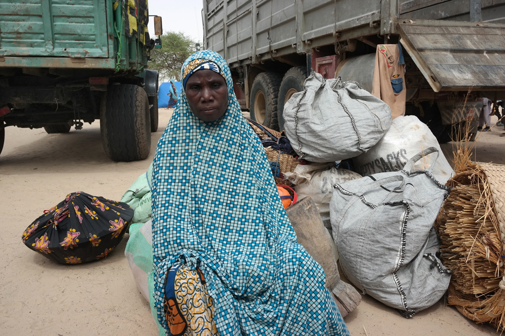 A Nigerian refugee woman awaits with her luggage to be transported from Garin Wanzam site to Sayam Forage camp. © UNHCR / Ibrahim Abdou