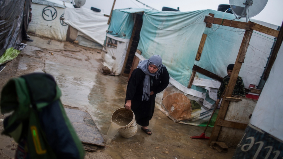 Syrian refugee Fatima sluices sewage away from her temporary home at an informal settlement on the outskirts of Zahle in the Bekaa Valley. 
