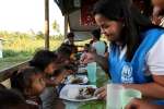  موظفة في المفوضية تساعد في إطعام الأولاد في المآوي الانتقالية في نيو كاوايان في جزيرة ليتي. يتناول الأولاد ممن هم دون الرابعة من العمر وجباتهم في خيمة صغيرة تقع عند مدخل الموقع.  