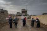 Recipients of UNHCR blankets walk back to their home after an aid dist...
