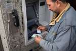 Syrian refugee Suhail Qamber uses a card provided by UNHCR to withdraw...