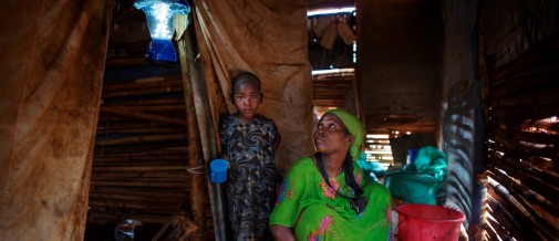 Refugee mother and her son in a shelter lit by one of UNHCR's solar lights.