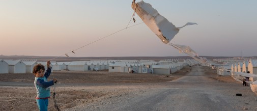 A young refugee boy in Azraq camp flying a homemade kite.