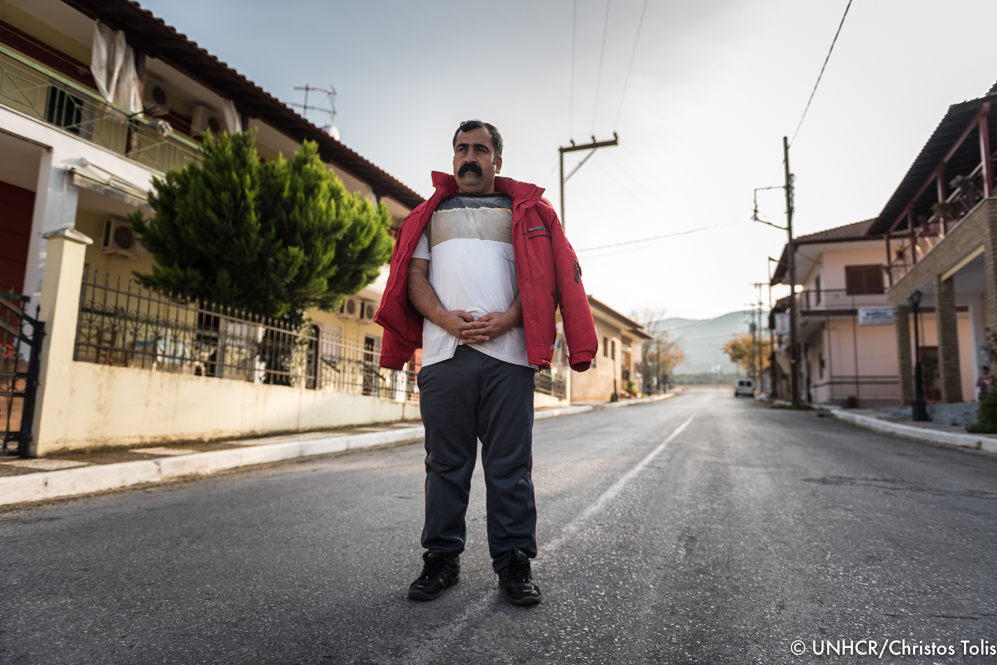 Ο Κheri Mando Sliman στέκεται στο δρόμο που συνδέει τη νέα του γειτονιά με τις όχθες της Λίμνης Βόλβης. © UNHCR/Χρήστος Τόλης