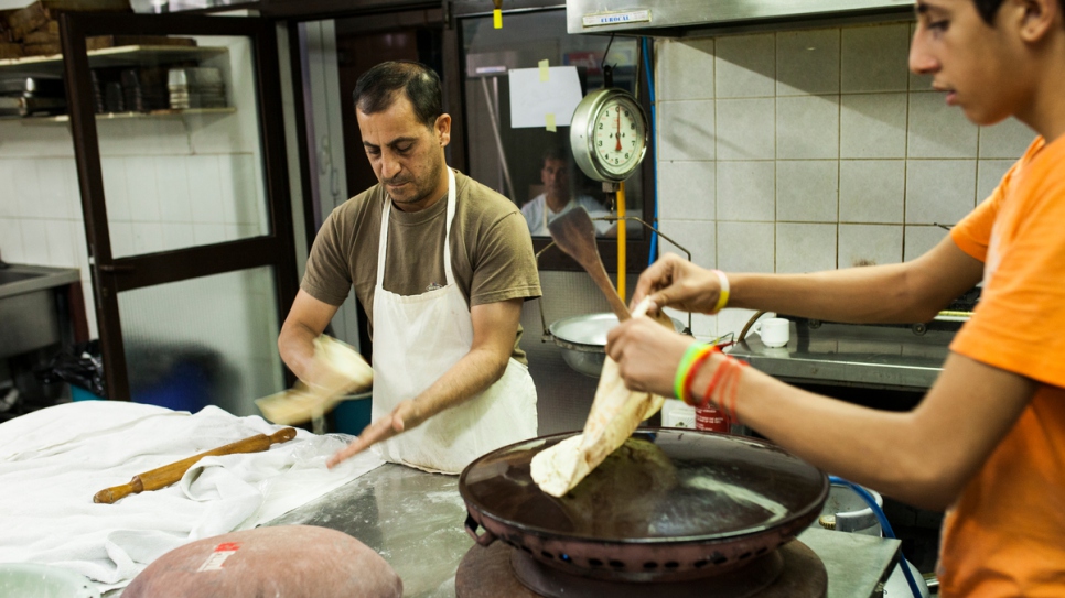 Syrian refugees prepare traditional bread in the kitchen of the Rovies Hotel. 