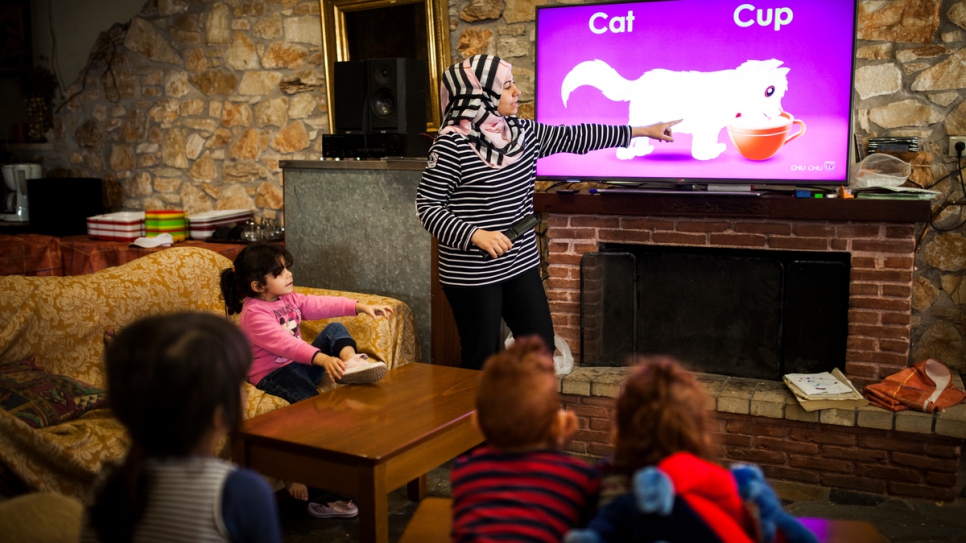 Manar, a Syrian refugee who fled home with her three children, teaches English to a group of young children.