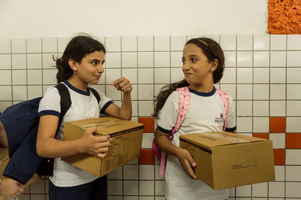 Hanan collects her city-issued school uniform with new friend Andressa.