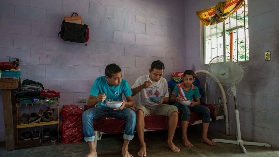 Moises, Anderson and Jairo eat breakfast in the room where they live.